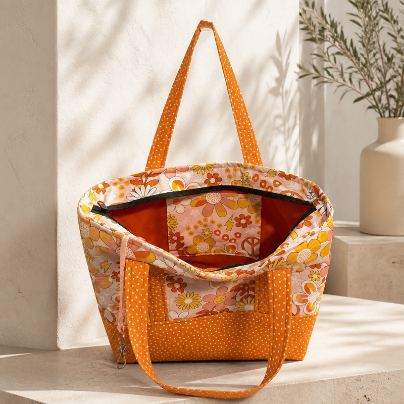 A handmade tote bag with a retro floral pattern and orange polka-dot straps, two interior pockets, one exterior zippered pocket. Lobster claw interior clasp for keys, or order matching wallet